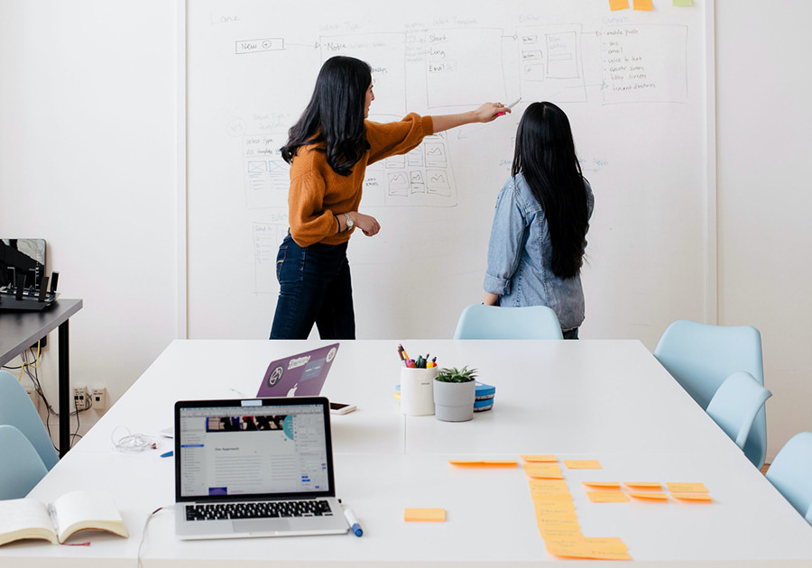 Two women brainstorming ideas at a whiteboard