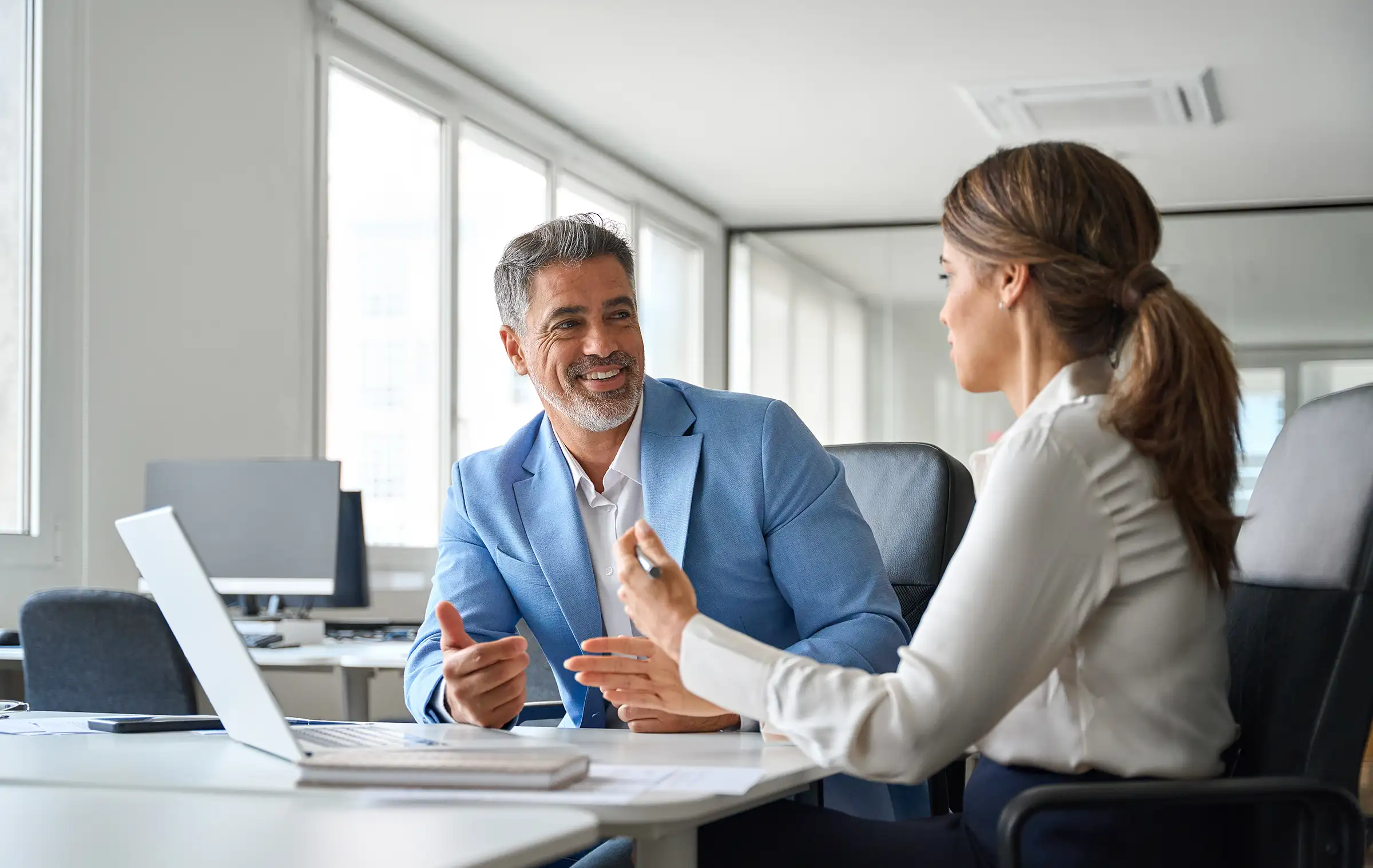 pros Two business professionals discussing ideas beside a laptop in an office